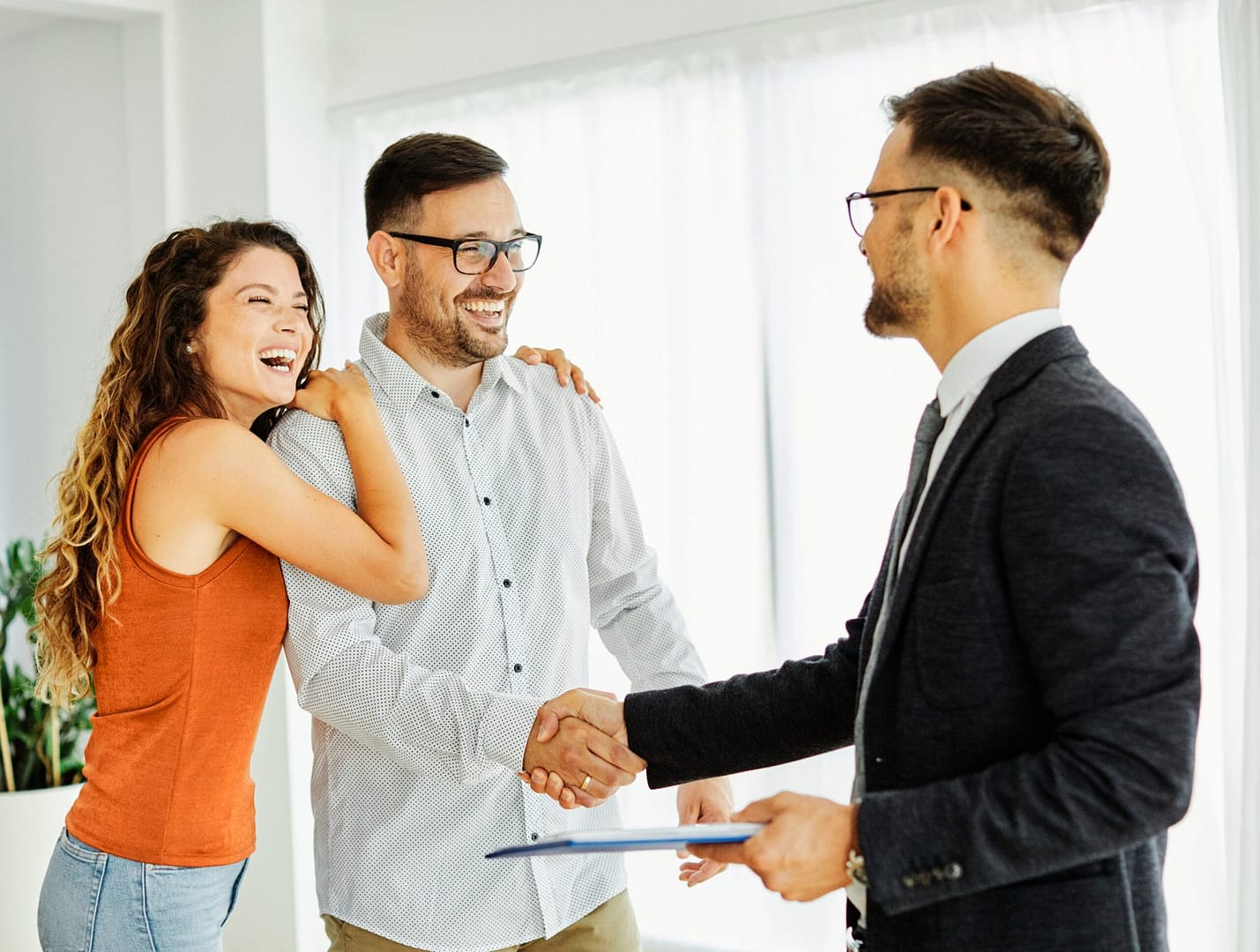 Young happy couple and an agent in a new property